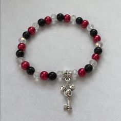 a red and black beaded bracelet with a key charm