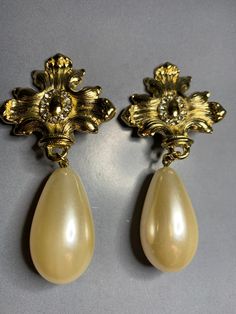 STUNNING VINTAGE 1980s BRIDAL GOLD TONE FAUX BAROQUE PEARL STYLE SPARKLING CRYSTALS MALTESE CROSS WEDDING BIG STATEMENT DANGLY CLIP ON EARRINGS !! A GORGEOUS pair of vintage 1980s dangly earrings !! These earrings feature a BEAUTIFUL glamorous style big statement faux baroque pearl , then a maltese cross with stunning sparkling CRYSTALS. Very high quality ! This pair is so unique and a TRULY eyecatching piece ! Perfect for your loved ones special wedding day or for any occasion as these earrings can be matched with any of your desired outfits !!  MEASUREMENTS: Length of the earrings is 7.5cm and the width is 3.5cm Condition: In ABOVE excellent vintage condition. The clips are secure and tight. There is no gold plating missing and no damage to the earrings. Please look at the photos as they Vintage Clip-on Bridal Earrings For Wedding, Vintage Bridal Earrings For Wedding, Vintage Style Gold Bridal Earrings For Formal Occasions, Vintage Gold Bridal Earrings For Wedding, Vintage Pearl Drop Bridal Earrings For Party, Gold Clip-on Bridal Earrings For Evening, Cross Wedding, Pearl Beach, Starfish Pendant