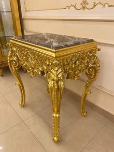 a golden bench with a marble top on the floor next to a wall and mirror