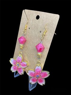 This is a pair of handcrafted earrings made out of resin. Featured is a pink and white flower with a pink bead embellishment. Pink Flower-shaped Resin Jewelry, Pink Flower Charm Dangle Jewelry, Rose Red Flower Earrings, Resin Flower Charm Dangle Earrings, Dangle Resin Flower Charm Earrings, Resin Dangle Flower Earrings With Flower Charm, Handmade Pink Flower Drop Earrings, Adjustable Pink Flower-shaped Jewelry, Adjustable Pink Jewelry With Handmade Flowers