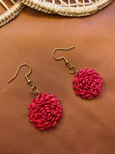 a pair of red earrings sitting on top of a brown table next to a wicker basket