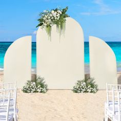 an outdoor ceremony setup on the beach with white chairs and flowers in front of it