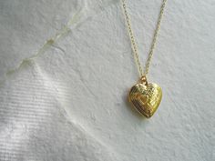 "A golden heart locket hangs from a gold chain. Please select a length from the drop-down box. The locket measures 1\" x 3/4\". *We do not personalize nor insert pictures. The locket and chain are gold plated over brass, so it's recommended removing before showering, swimming, etc. to keep jewelry looking like new." Gold Heart Locket Necklace For Memorial, Gold Brass Heart Pendant Locket Necklace, Gold Heart Pendant Locket Necklace In Brass, Gold Heart Pendant Locket Necklace For Memorial, Gold Heart Necklace With Vintage Charm For Anniversary, Gold Heart Charm Locket Necklace For Memorial, Gold Heart Necklace With Vintage Charm For Gift, Gold Open Heart Locket Necklace, Gold Heart Necklace For Memorial