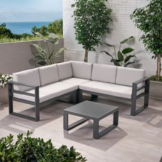 a couch and table sitting on top of a patio next to a wall with plants