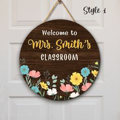 a welcome sign hanging on the front door of a classroom with flowers painted on it