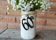 a white mason jar filled with baby's breath flowers and the number 50 painted on it