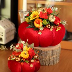 two red pumpkins with flowers on them sitting on a table next to each other