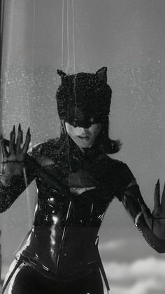 a woman dressed in latex is holding her hands out to the side while wearing a cat mask