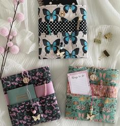 three small purses sitting on top of a bed next to flowers and writing utensils