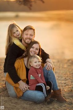 a man, woman and child are sitting on the beach at sunset with their arms around each other