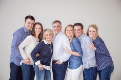 a group of people standing next to each other in front of a white wall with their arms around each other