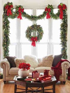 a living room decorated for christmas with wreaths on the windowsill and poinsettis