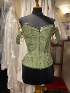 Green overbust corset with cording panels and detachable straps, made in apple green silk brocade and cream woven cotton lining. This corset is meant to be worn to emphasise the classic hourglass silhouette. Offers up to 10 cm waist reduction.  Plastic boning and metal busk.  This beauty is available in a number of different colours and fabrics and completely customisable, message me for more details! MEASUREMENTS: This item is available to be made to order, you must provide me with the followin Green Wedding Corset Dress, Green Fitted Corset Dress For Formal Events, Green Fitted Corset Dress For Formal Occasions, Historical Underbust Corset With Fitted Bodice, Elegant Fitted Corset With Historical Design, Elegant Corset Belt For Costumes, Elegant Overbust Bodice For Costume, Elegant Costume Corset With Boning, Elegant Corset With Historical Design For Costume Party