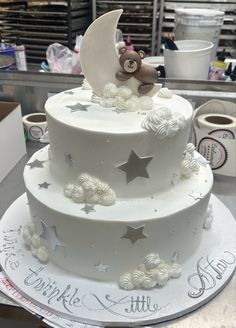 a three tiered cake decorated with stars and a teddy bear on top