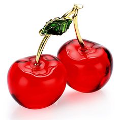 two shiny red cherries with green leaves on them