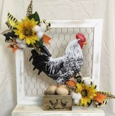 a chicken and some flowers are on a shelf next to an egg carton with eggs in it