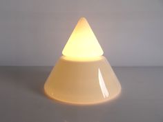 a white light sitting on top of a table next to a gray wall and floor