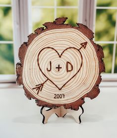 a heart carved into a piece of wood with an arrow in the center and initials on it