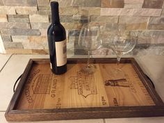 a bottle of wine sitting on top of a wooden tray next to two empty glasses