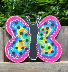 a colorful butterfly sitting on top of a wooden fence