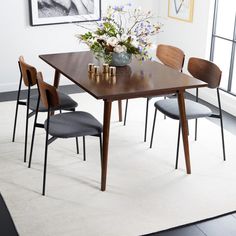 a dining table with four chairs and a vase filled with flowers on top of it