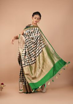 Amp up your style quotient with this trendy checks pattern handwoven on pure katan silk. Black and Off White yarn come together in this play of a classic pattern with opulent Banarasi border in green with antique Gold zari. The banarasi zari buttas interspersed along the checks adds elegance. The signature zari pallu of a Banarasi saree with intricate gold zari weave completes the look.  SILK MARK CERTIFIED This saree is ready to wear with fall and pico done. Handmade silk tassels adorn the pallu and add more grace to it. An unstitched blouse fabric is included. *Note: There may be minor variations in the shade, the texture of the product. Hues/textures show differently due to variations in screen settings and other factors, *Note: This is a handwoven saree and there may be slight inconsis Luxury Green Banarasi Silk Dupatta, Luxury Green Banarasi Silk Traditional Wear, Luxury Green Katan Silk Dupatta, Luxury Banarasi Silk Sets With Zari Weaving, Luxury Katan Silk Traditional Wear With Zari Weaving, Saree In Black, Checks Pattern, Silk Banarasi Saree, Silk Tassels