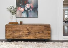 a wooden chest sitting on top of a white rug next to a vase filled with flowers