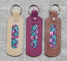 three leather key fobrings with floral designs on them are sitting next to each other