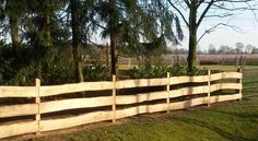 a wooden fence in the middle of a grassy field