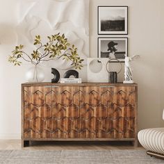 a living room with a wooden cabinet and pictures on the wall above it, along with a white chair