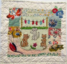 a quilted wall hanging with cats and flowers