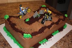 a cake shaped like a dirt bike track with two people riding motorcycles on the top