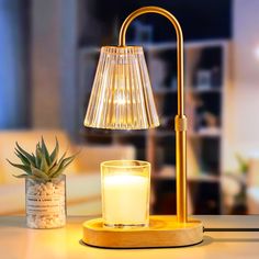 a table lamp next to a candle and a potted plant