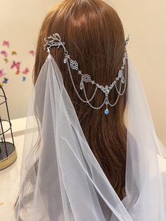 a woman wearing a veil and head piece with jewels on it's head is seen from the back