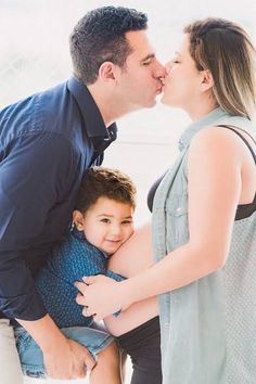 a man and woman kissing their son on the cheek