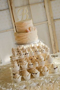 a wedding cake and cupcakes on a table