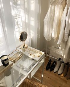 a white desk topped with a mirror next to a pair of shoes and a lamp