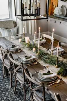 a dining room table set with candles and place settings