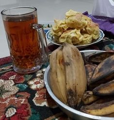 bananas and other food on a table with a glass of tea next to it,