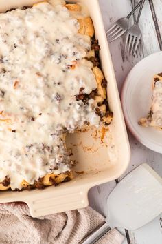 a casserole dish with meat and cheese covered in gravy next to a fork