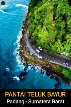 an aerial view of a road near the ocean with cars driving on it and trees in the background