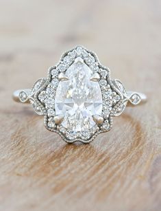 an oval shaped diamond ring on top of a wooden table