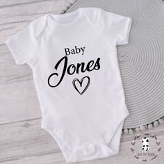 PERSONALISED WHITE BODYSUIT/VEST - AVAILABLE IN LONG OR SHORT SLEEVE AND VARIOUS SIZES All our vests are finished with high quality vinyl with a lovely soft touch and made from 100% cotton Colour of text and heart can be changed, Just add a note at the checkout along with the name you would like on the vest. A lovely gift for those special relatives and friends. We create personalised gifts for all occasions each with different designs and colours to choose from. Personalised gifts for any occas Family Matching White Bodysuit For Gender Reveal, White Family Matching Bodysuit With Name Print, White Summer Bodysuit For Gender Reveal, White Bodysuit For Summer Gender Reveal, White Fitted Top For Gender Reveal, White Short Sleeve Bodysuit For Gender Reveal, Baby Reveal, Baby Vest, White Bodysuit