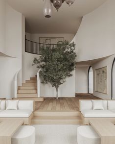 a living room filled with white couches and a tree in the middle of it