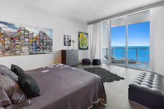 a bedroom with a large window overlooking the ocean and cityscape on the wall