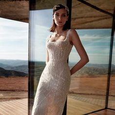 a woman standing in front of a glass wall wearing a dress with sequins