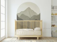 a baby's crib in a white room with mountains painted on the wall