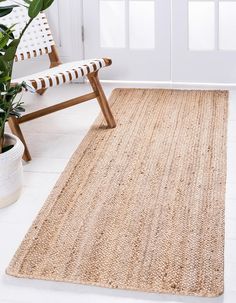 a large rug is on the floor in front of a chair and potted plant