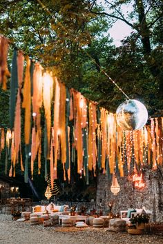 an outdoor party with orange streamers hanging from the ceiling and tables set up outside