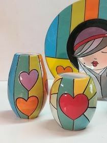 three colorful vases with hearts painted on them next to a plate and other items